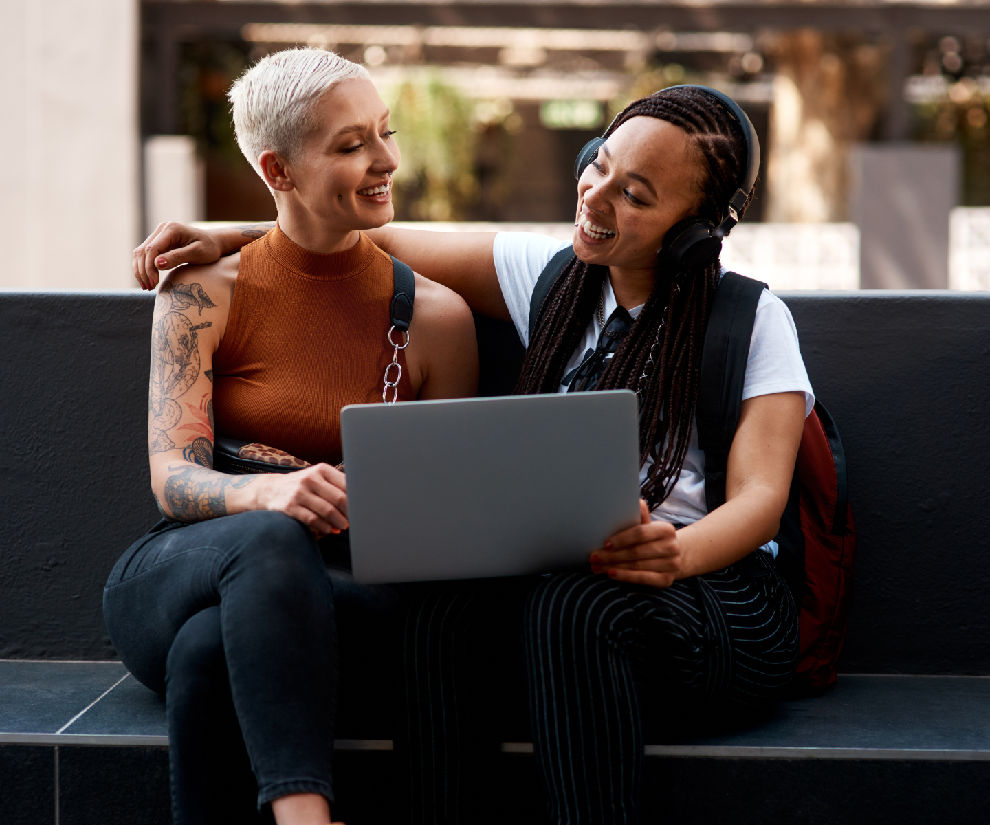 Two women sitting next to each other sharing a laptop.