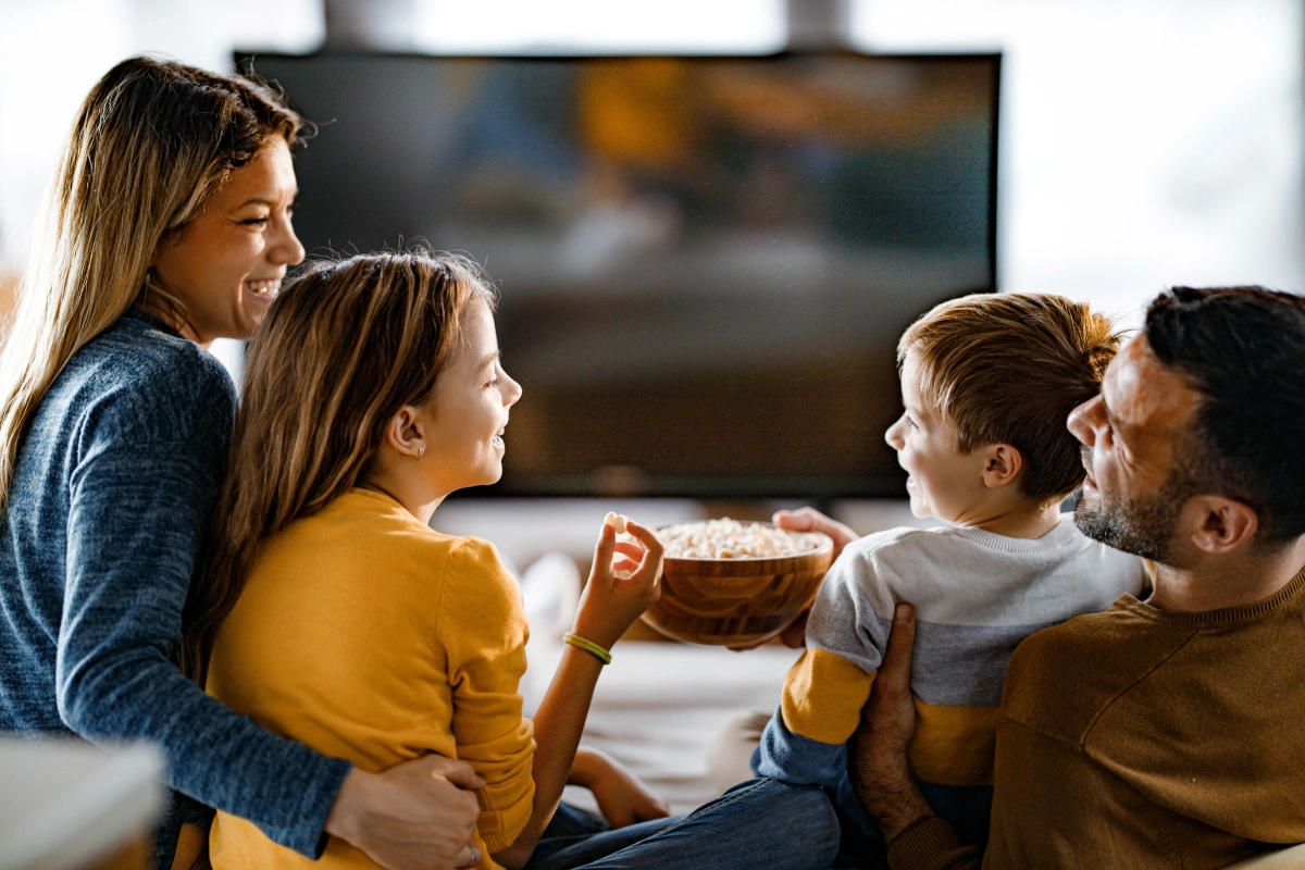 A family watching a movie and eating popcorn at home