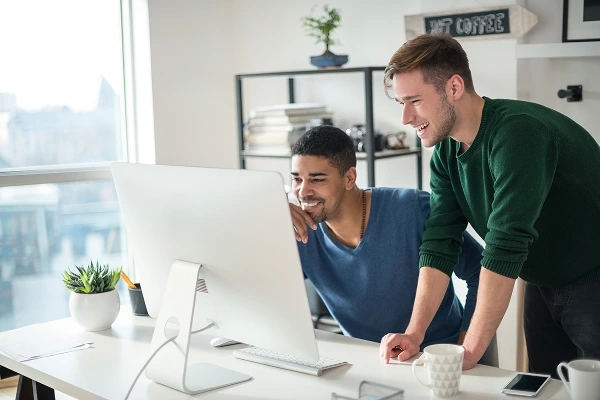 Two men in an office working in front of a computer monitor