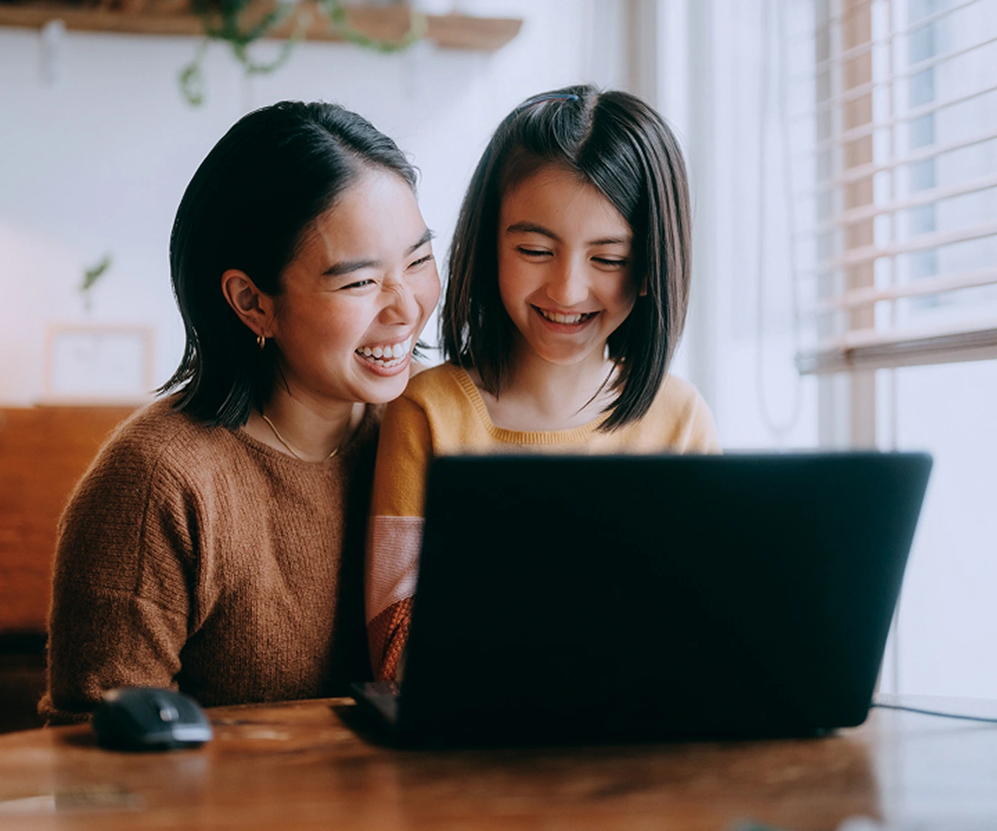 A mom with her daughter sitting on her lap using the laptop