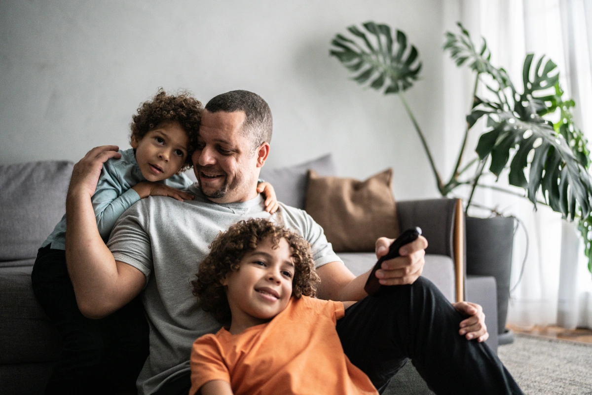 A father sitting with his two sons watching television