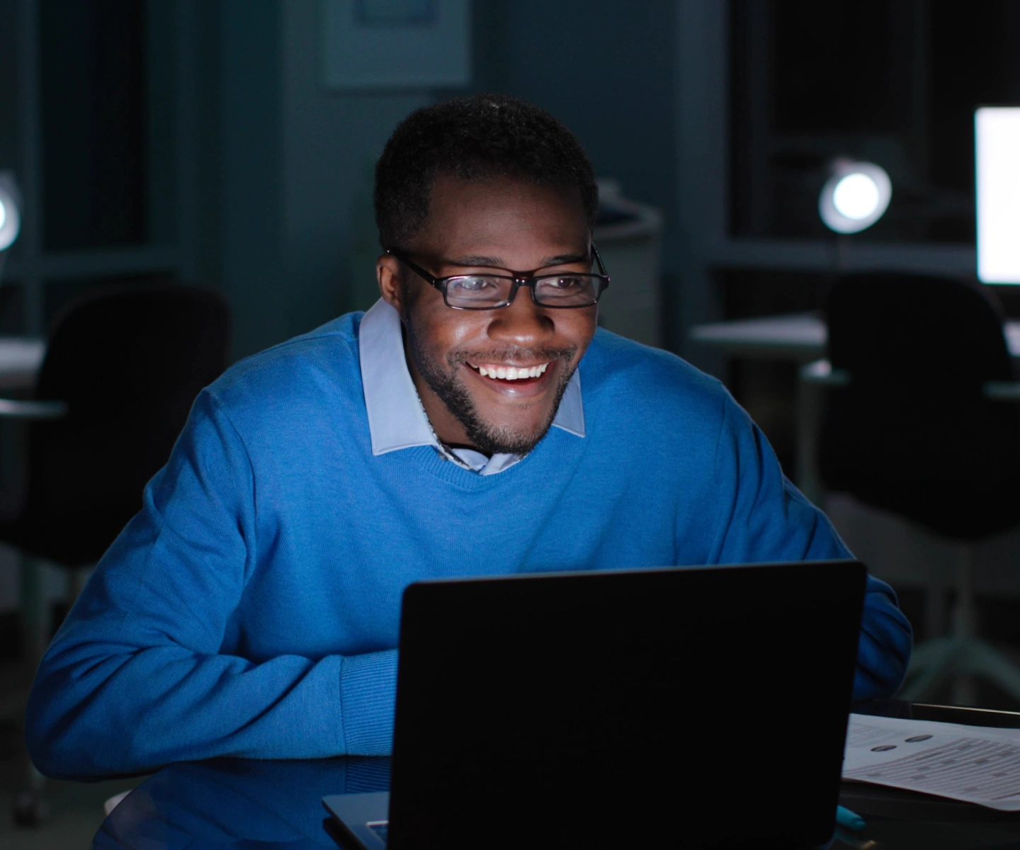 A man in a blue sweater at his desk using a laptop with Frontier internet to register an account