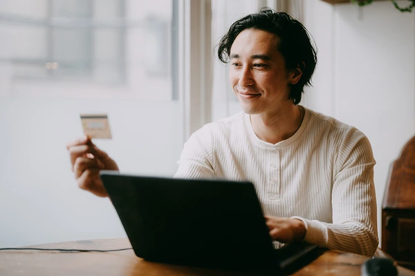 A young man holding a credit card making a purchase online