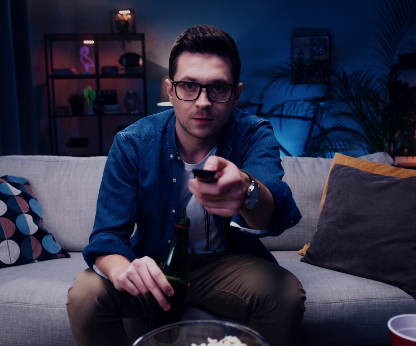 Man sitting on couch uses remote for TV