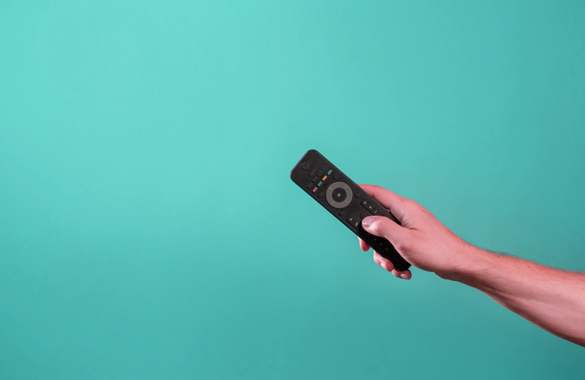 A TV remote in a person's hand