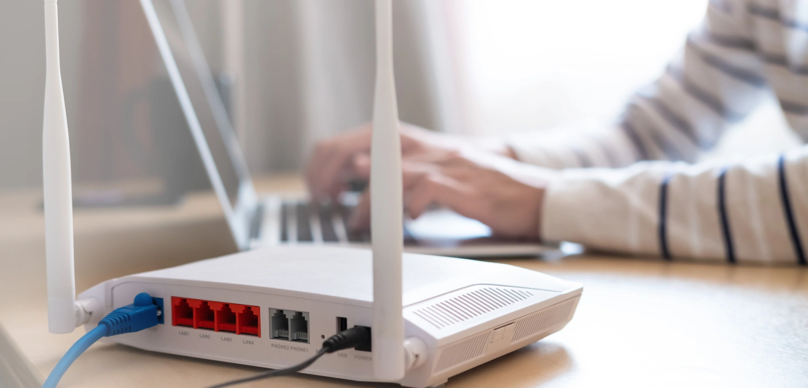 A router sitting on a desk and a person using a laptop