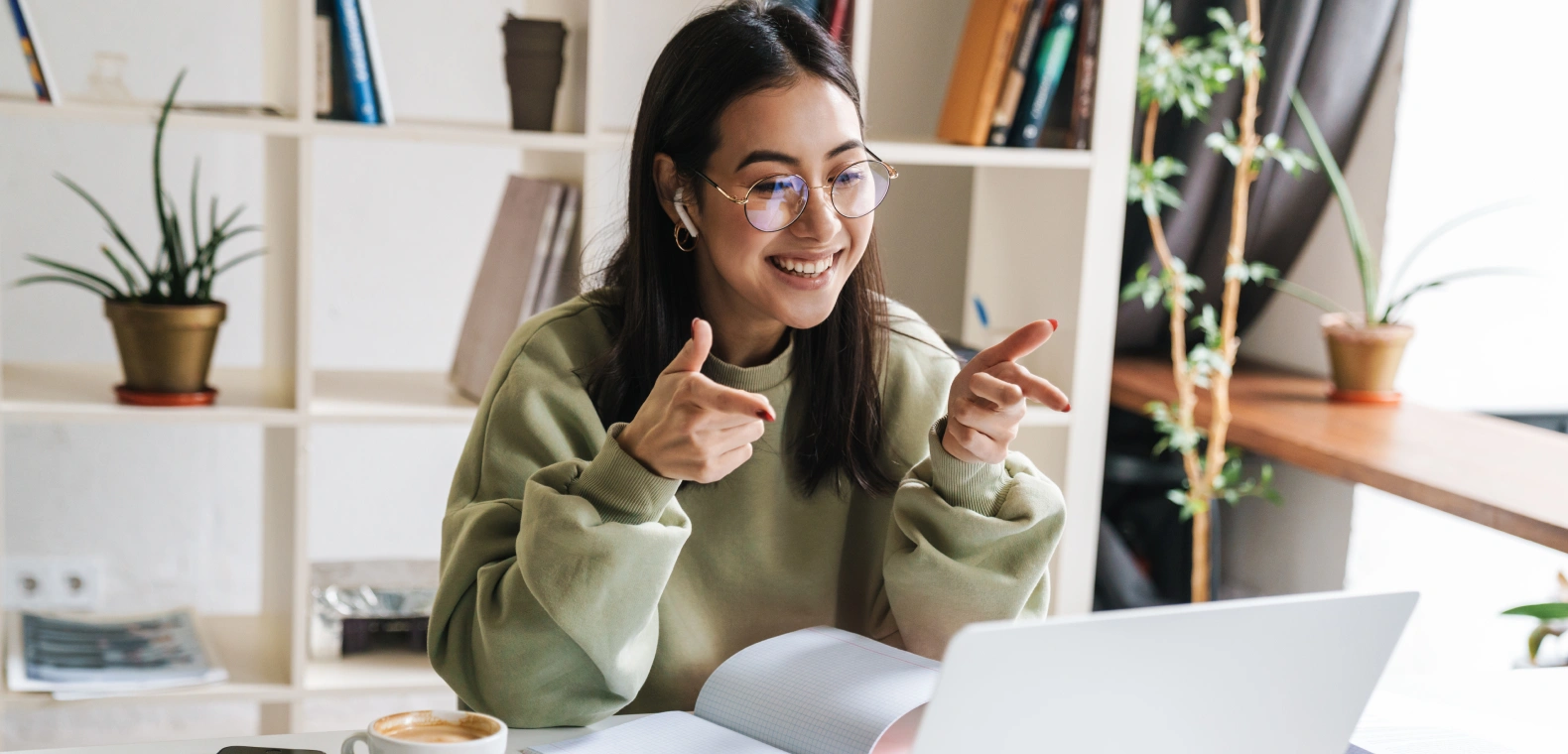 A woman in an office space with plants and books uses her laptop