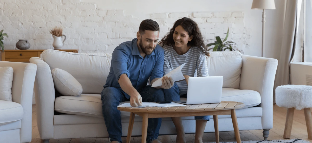 A couple sitting on the couch looking at paperwork