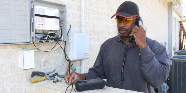 Man holding a phone outside a house while he sets up the connection