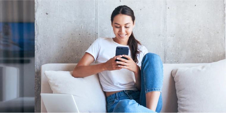 Woman sits on couch holding phone