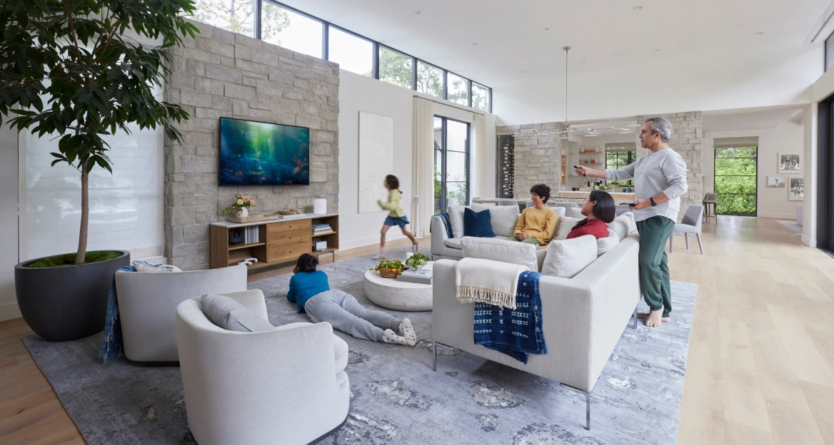 A family relaxes in a modern living room while using a TV and smart devices, illustrating a connected home internet experience.