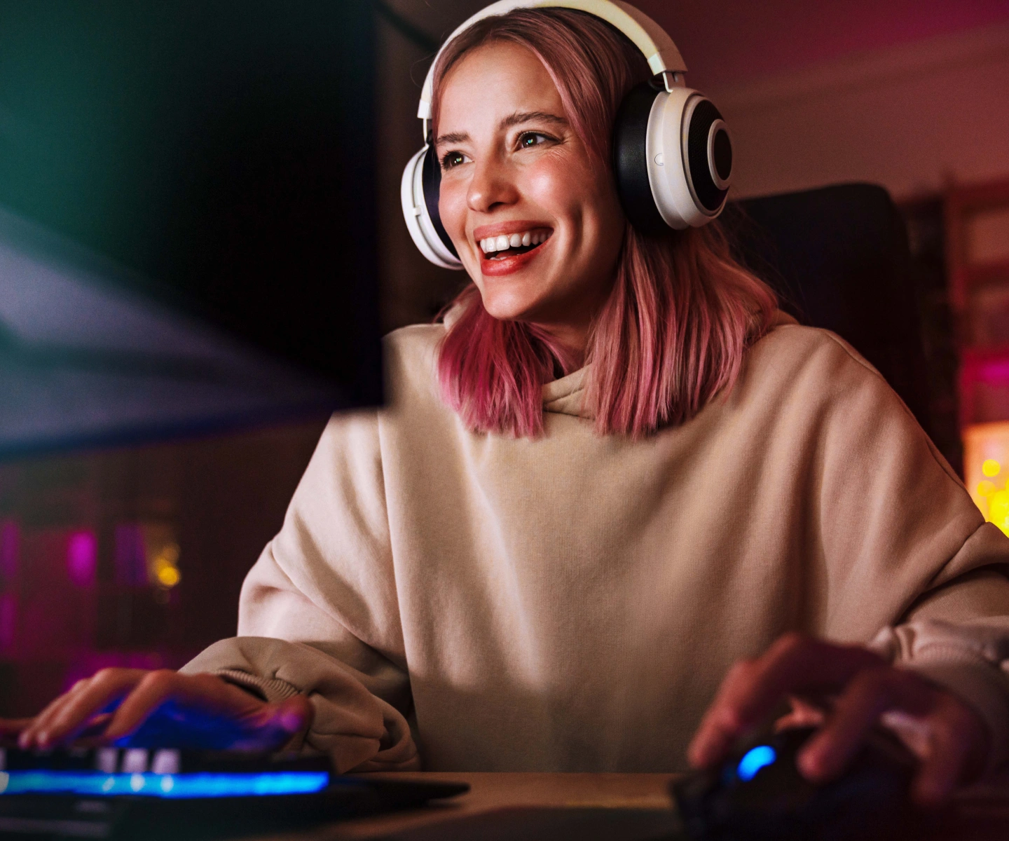 A happy young woman wearing headphones as she is gaming online with Frontier Fiber internet